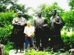 Writer standing among three statues of China's important figures