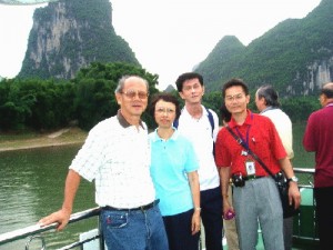Writer in white T-shirt, his wife and son, and tour-guide in red shirt on a cruise boat