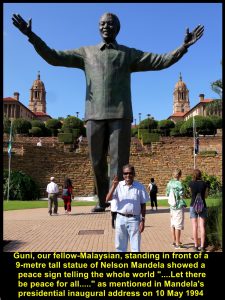 Guni, fellow-Malaysian, standing with a V-sign in front of a 9-metre tall statue of Nelson Mandela, Union Buildings, Pretoria