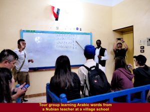 A Nubian teacher teaching tour group some Arabic words at a village school
